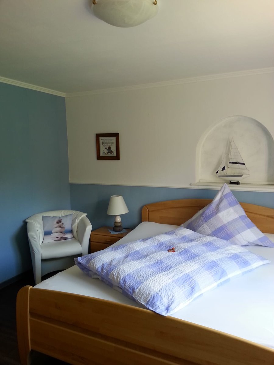 Zimmer mit Doppelbett und hellblau karierter Bettwäsche.