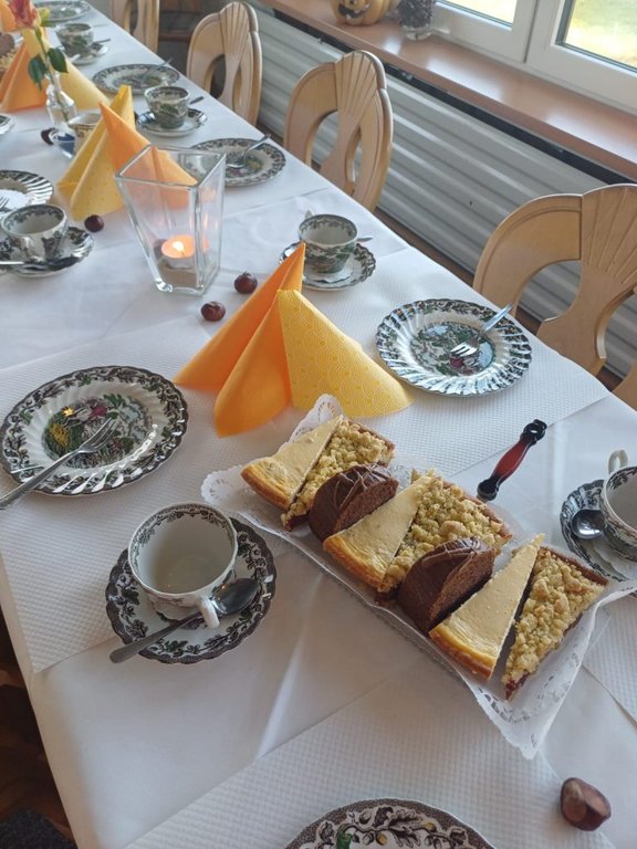 Bild zeigt einen eingedeckten Tisch im Gastraum mit Kuchenstücken auf einer rechteckingen Kuchenplatte.